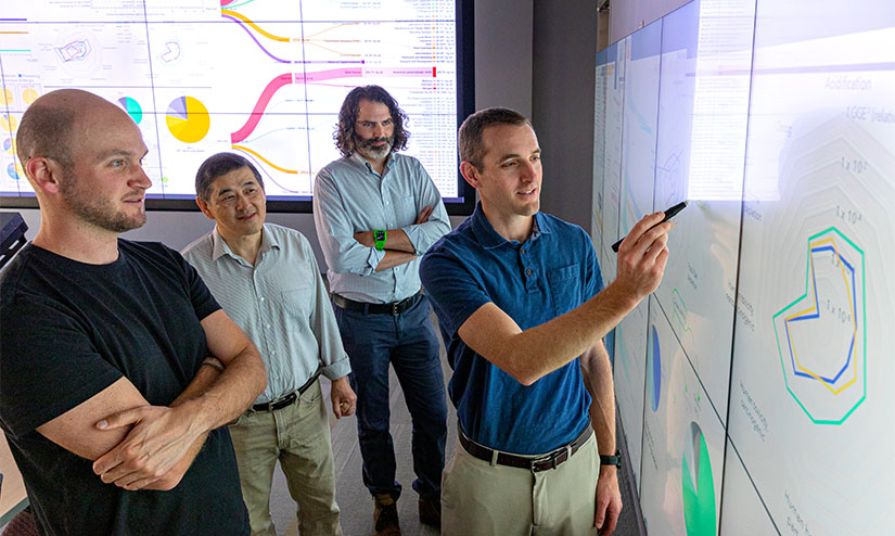 Four researchers examine data on a screen