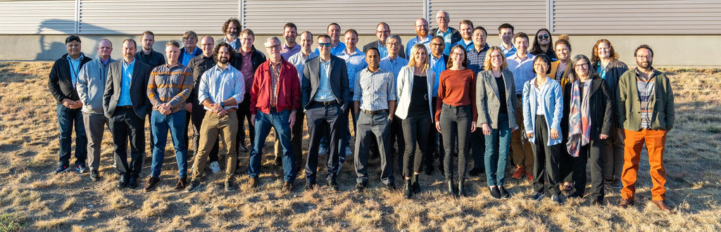 A group of 35 people pose for a photo outdoors.