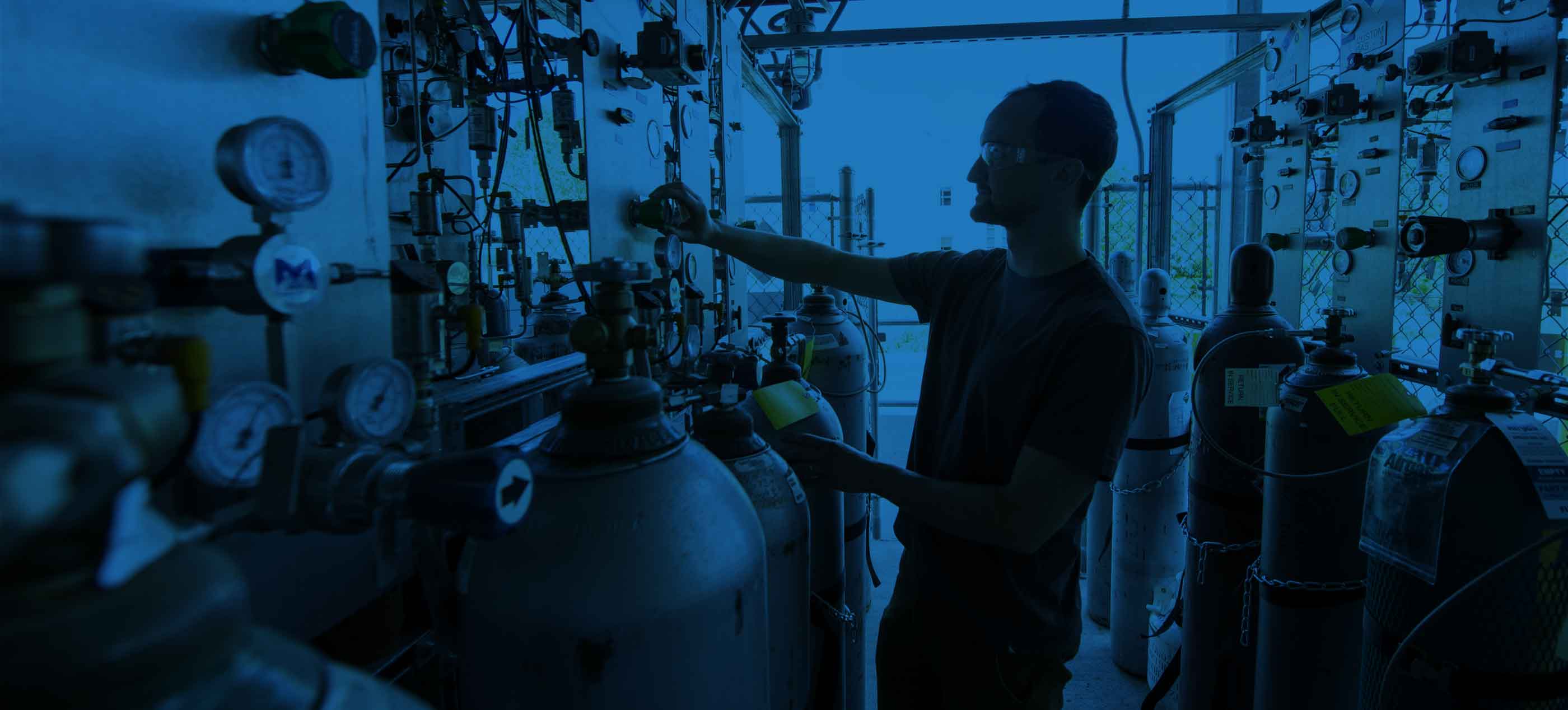 man working with various gas tanks in laboratory
