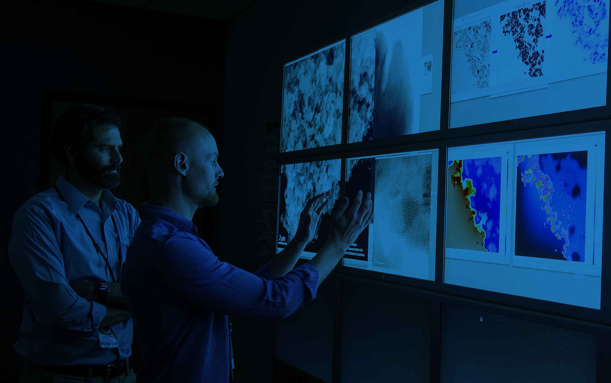 two men inspecting images on a large screen